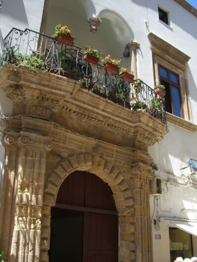 pittoresker Balkon mit Blumen über einem steinernen Eingangsportal in Gallipoli