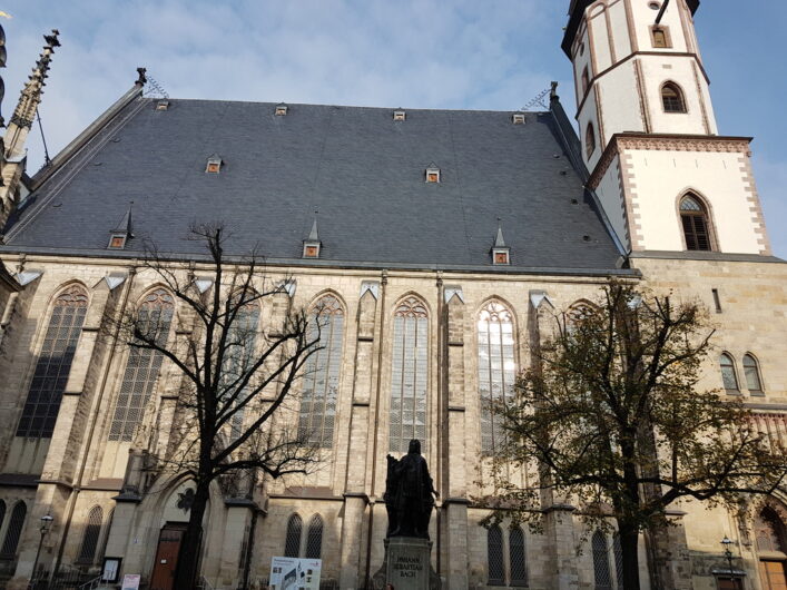 ein seitlicher Blick auf die Thomaskirche mit der Statue von Johann Sebastian Bach davor