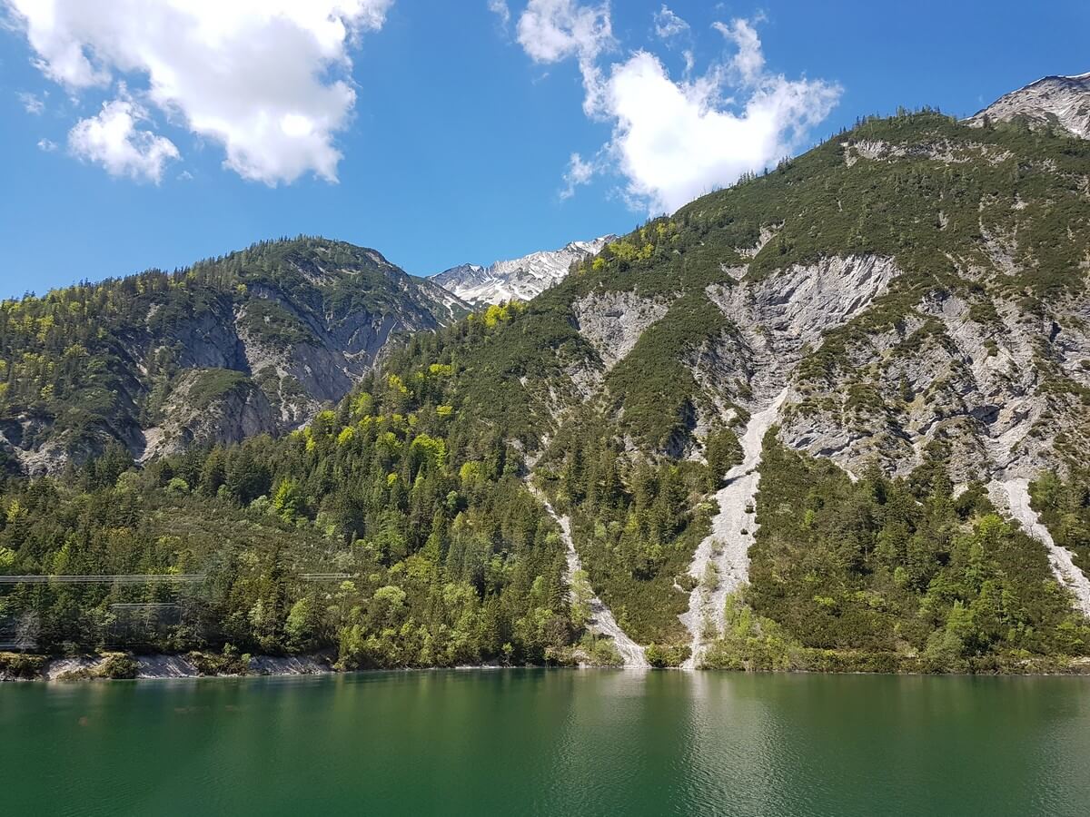 bewaldete Felsen reichen hinunter an das Ufer des dunkelgrün schimmernden Achensees