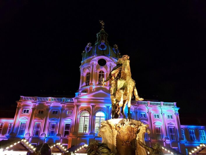 Blick auf das erleuchtete Schloss Charlottenburg und die Dächer der Weihnachtsmarktbuden