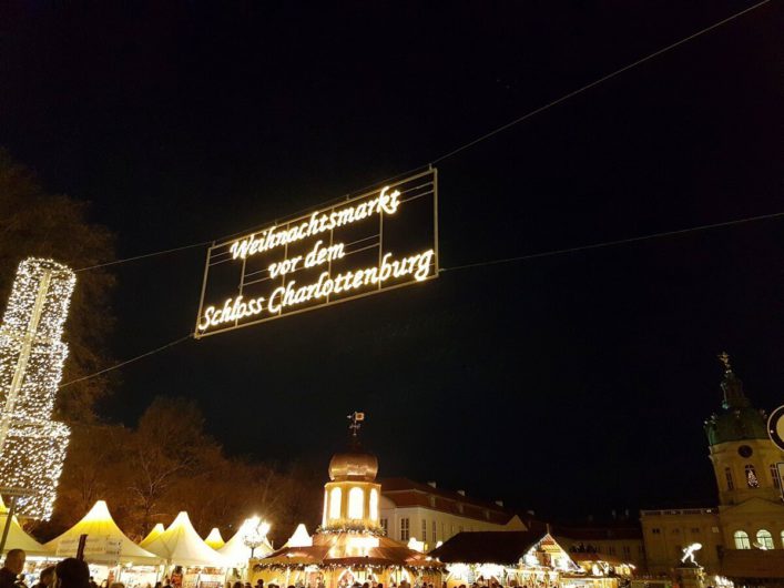 Eingang zum Weihnachtsmarkt am Schloss Charlottenburg mit den erleuchteten Ständen und dem Schloss Charlottenburg