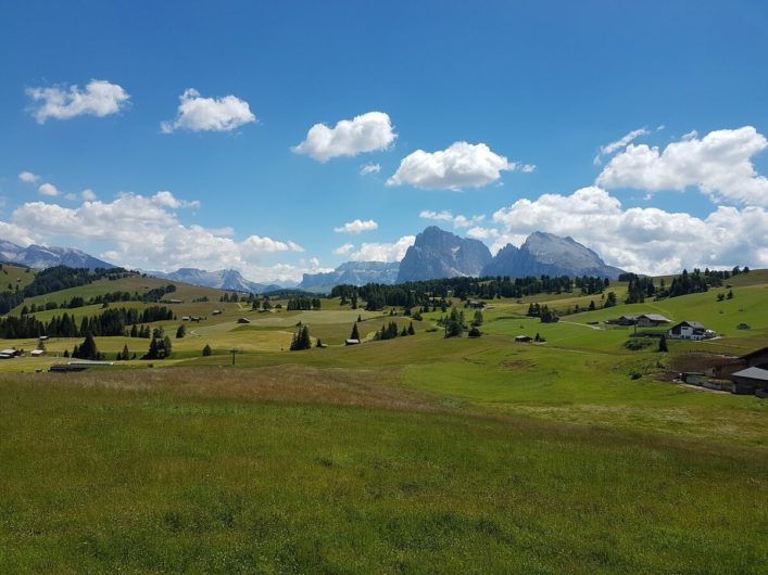 Blick über die saftigen Wiesen der Seiser Alm bis hin zu den Gipfeln der Dolomiten