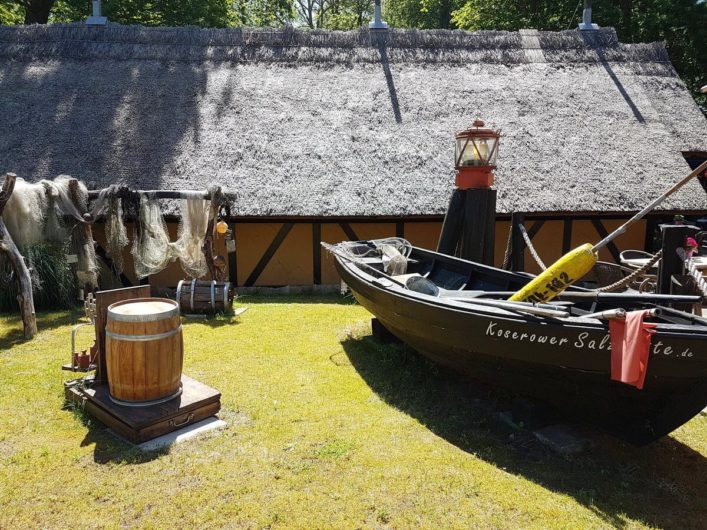 Salzhütten in Koserow mit altem Holzfass und Fischerkahn davor