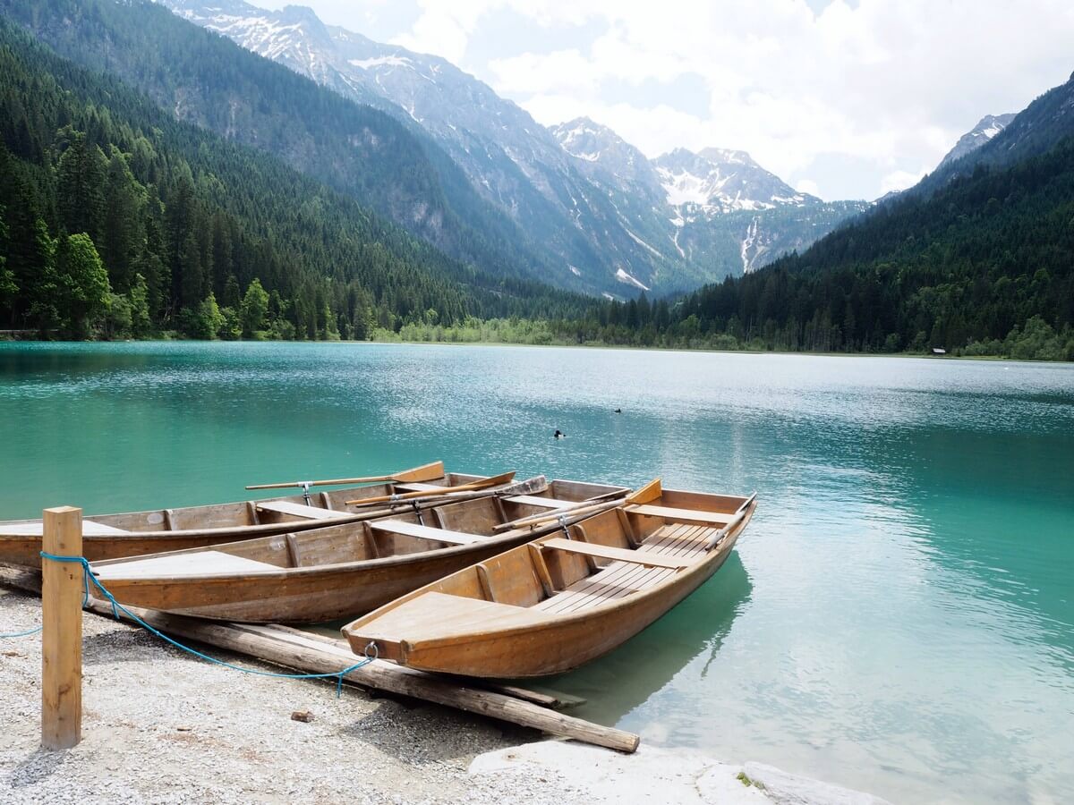 2 Holzboote auf dem grün-blau schimmernden Jägersee vor einer Bergkulisse