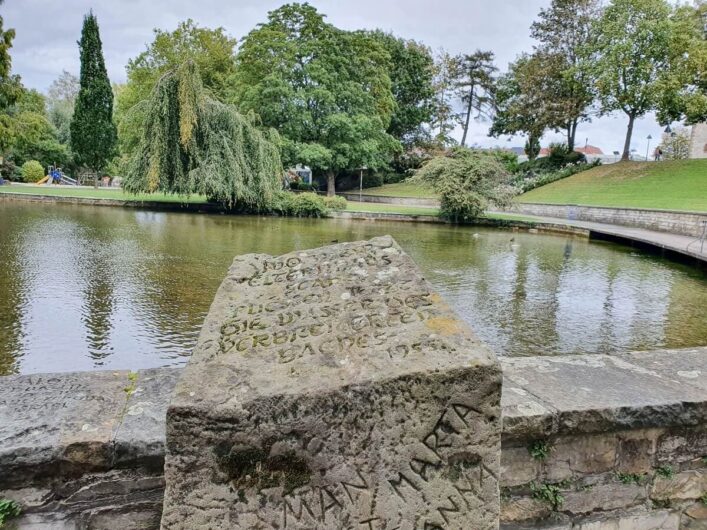 Stein mit Aufschrift vor einem Paderquellbecken