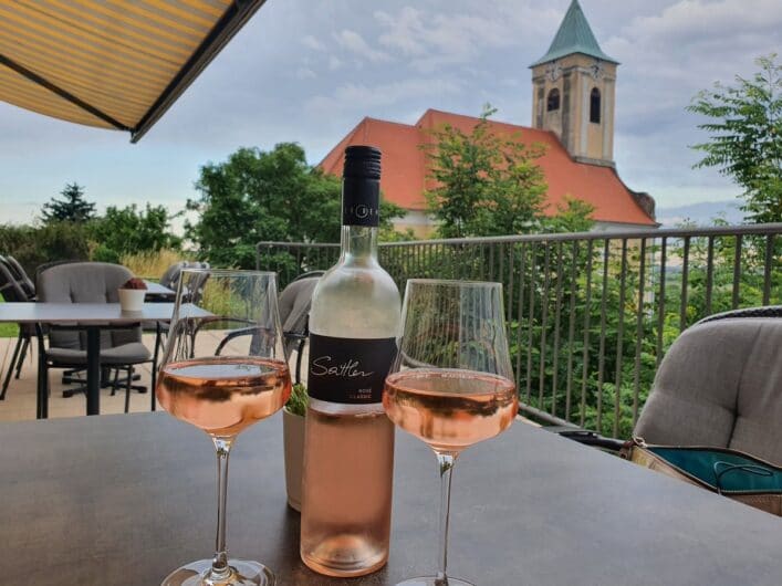 Roséwein in Gläsern und die Dorfkirche von Jois