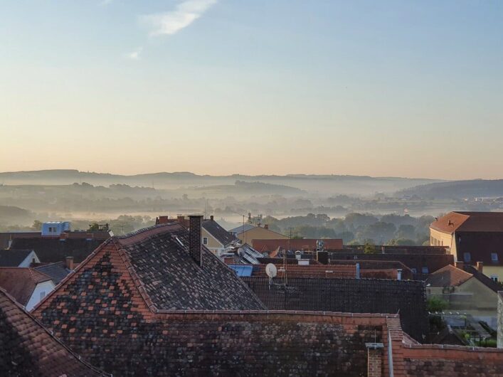 Blick über die morgendlichen Dächer von Hartberg in der Steiermark auf die Hügel der Region.