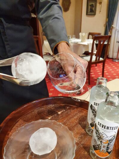 Ein großer Eisball wird als Kühlung für den Gin ins Glas gegeben