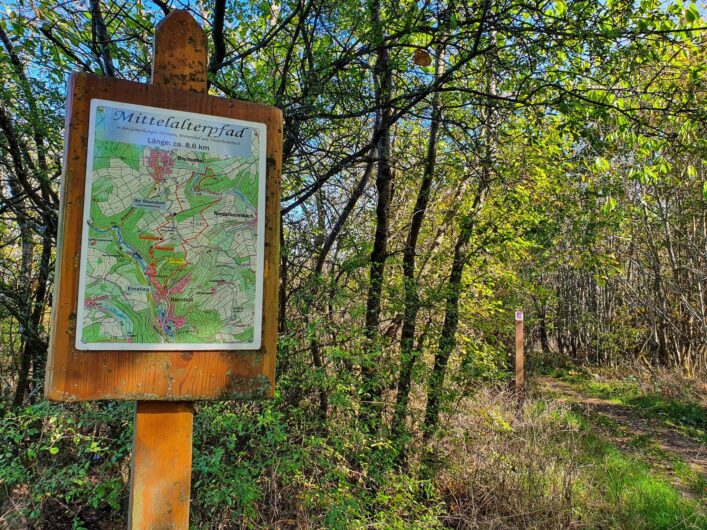 Hinweisschild zum Mittelalterweg im Wald