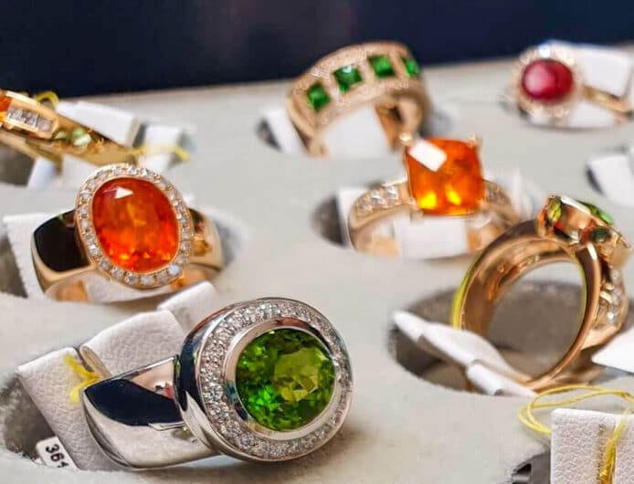 Ringe mit orangenen und grünen Steinen auf Präsentiertablett