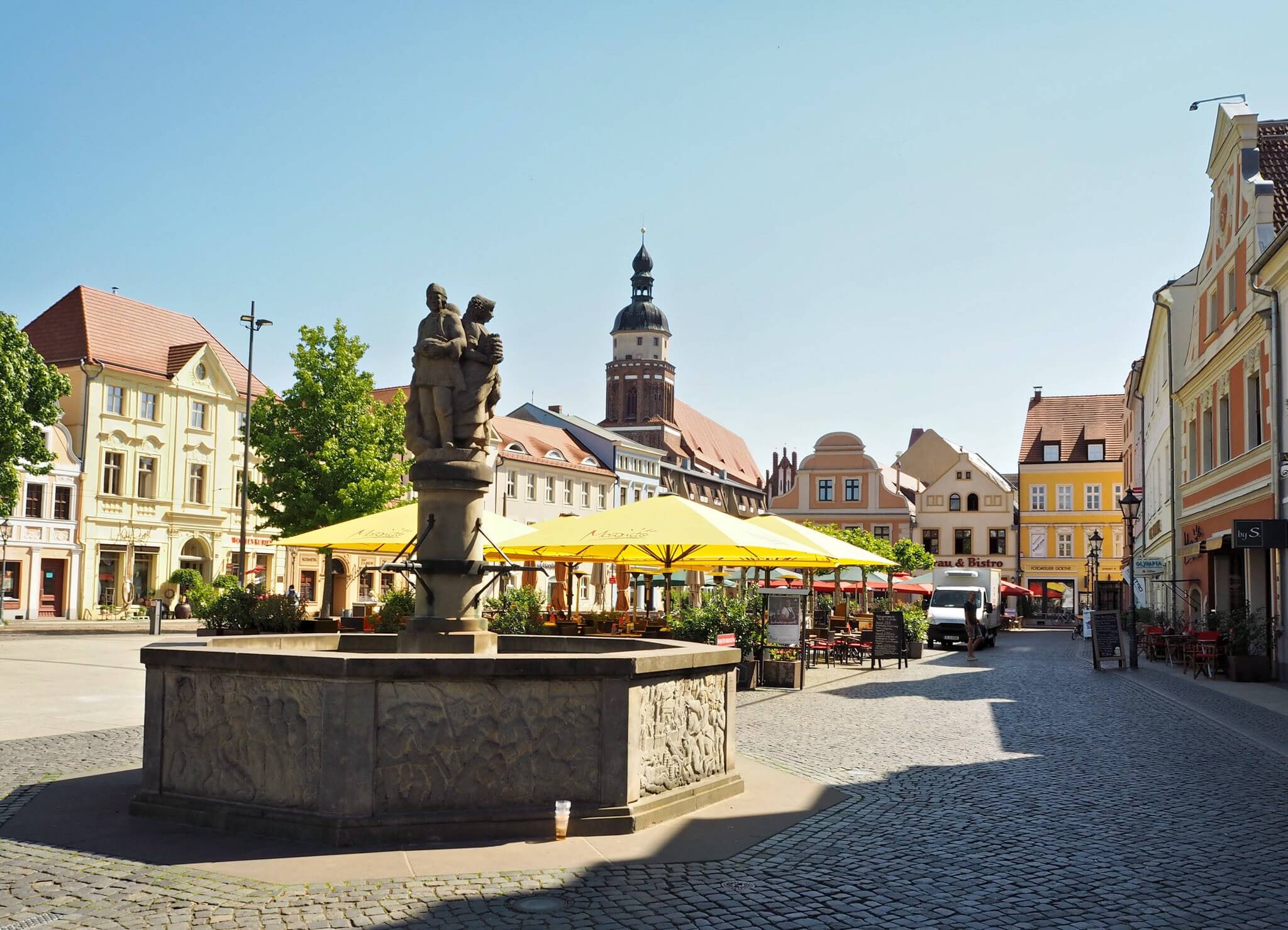 Marktplatz Cottbus mit Brunnen, Sonnenschirmen und Kirche im Hintergrund