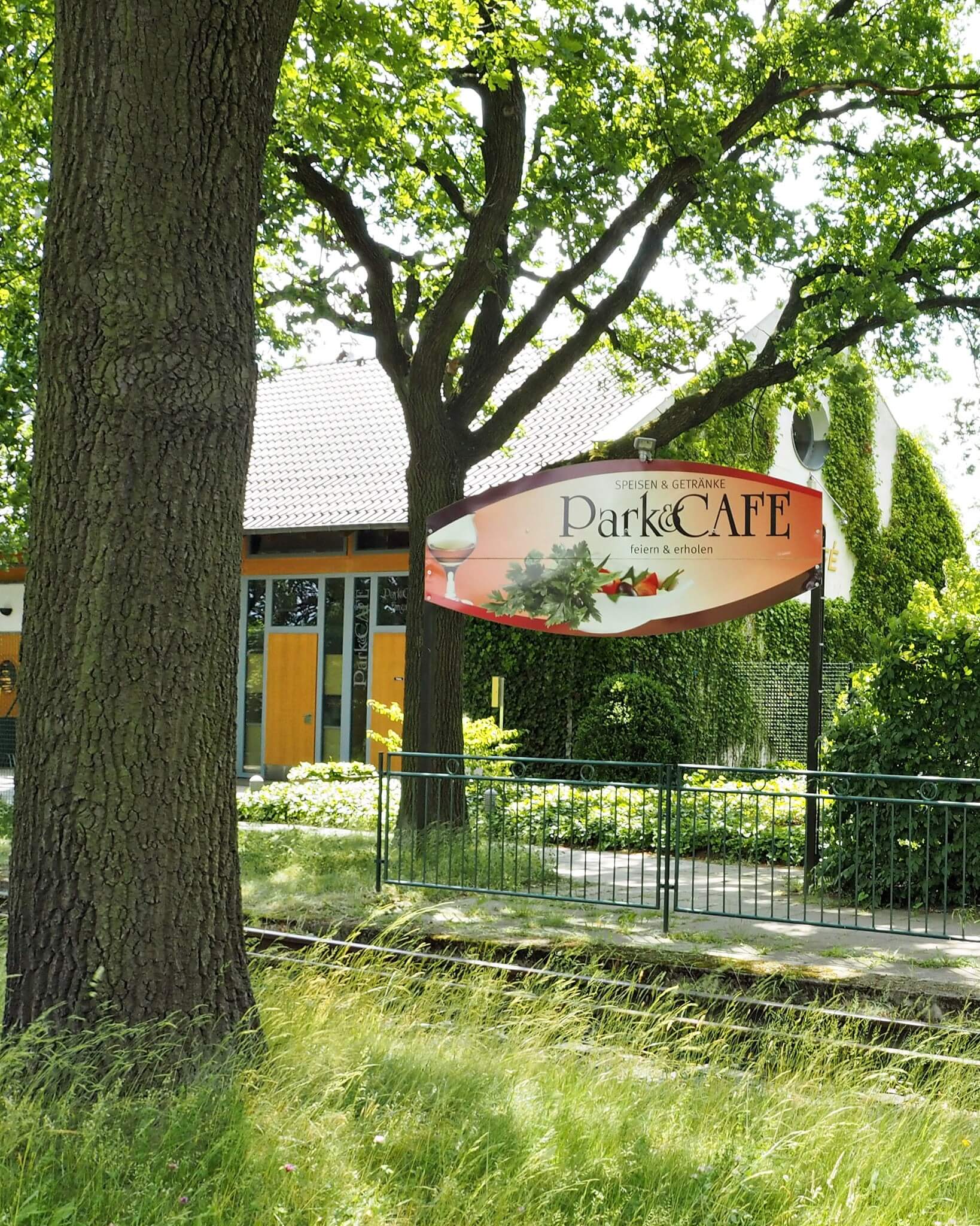 Hinweisschild auf das Parkcafé direkt an den Schienen der Parkeisenbahn