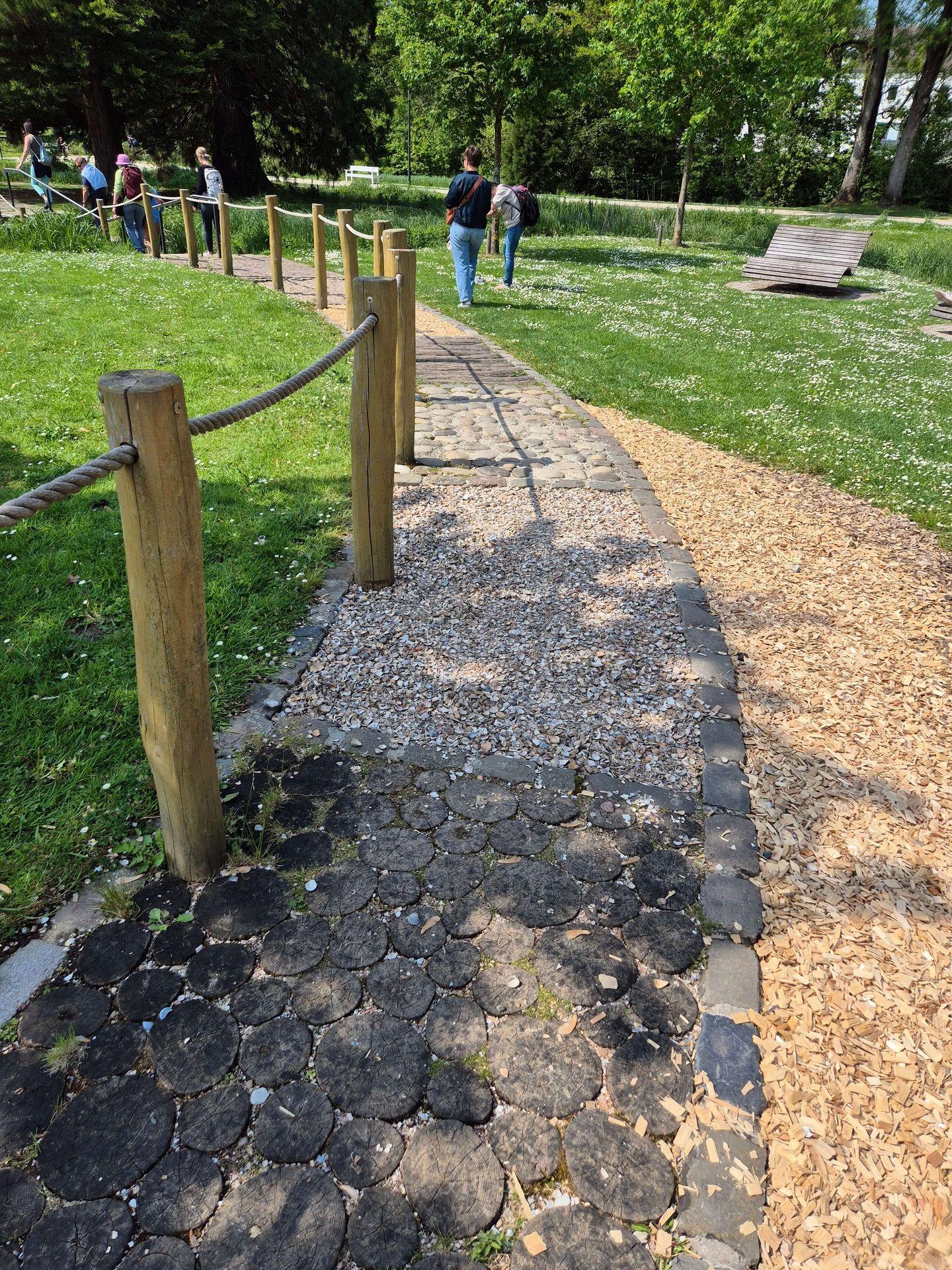 Barfußpfad im Kurpark Bad Sassendorf mit verschiedenen Bodenbelägen aus Holzscheiben, Kieselsteinen und Rindenmulch.