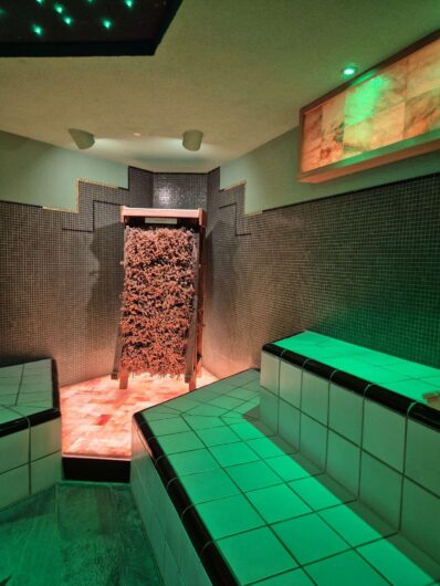 Dampfbad der Börde-Therme in Bad Sassendorf mit gefliesten Sitzbänken, grünlicher Beleuchtung und einem Reisigbündel.