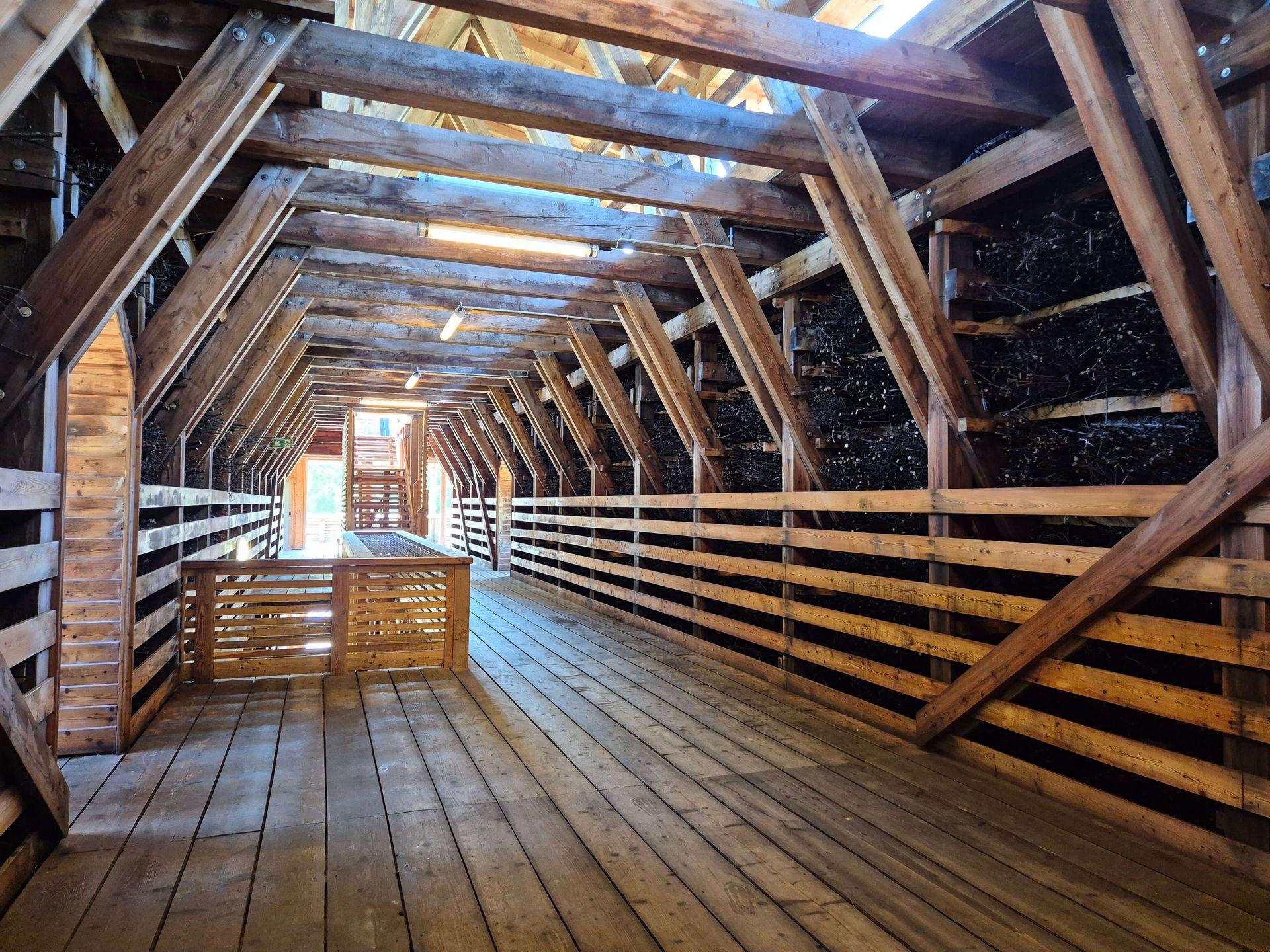 Überdachter Holzgang im Gradierwerk Bad Sassendorf mit massiven Holzbalken, Schwarzdornreisig und einem Steg für Besucher.