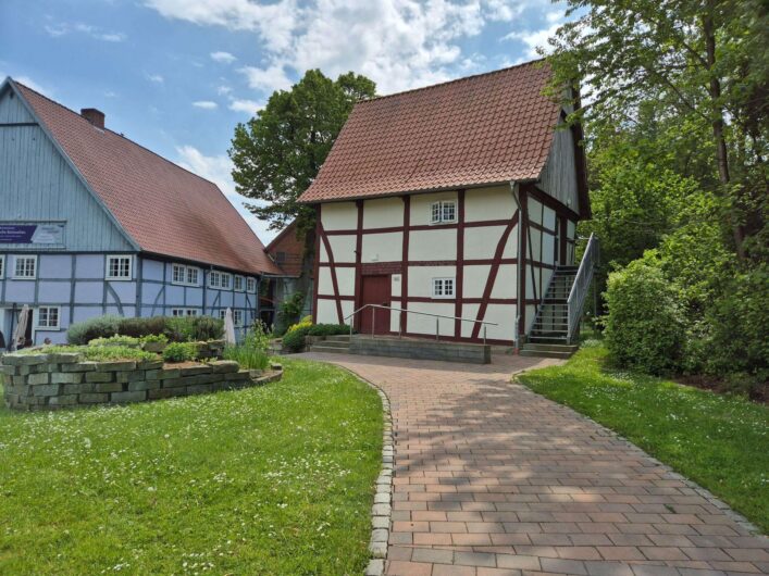 Historische Fachwerkgebäude der Westfälischen Salzwelten in Bad Sassendorf mit roten Ziegeldächern, gepflegten Grünflächen und einem gepflasterten Spazierweg.