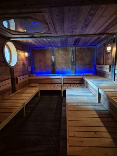 Innenraum der Gradierwerksauna in Bad Sassendorf mit mehrstufigen Holzbänken, Bullaugenfenstern und blauer Beleuchtung.