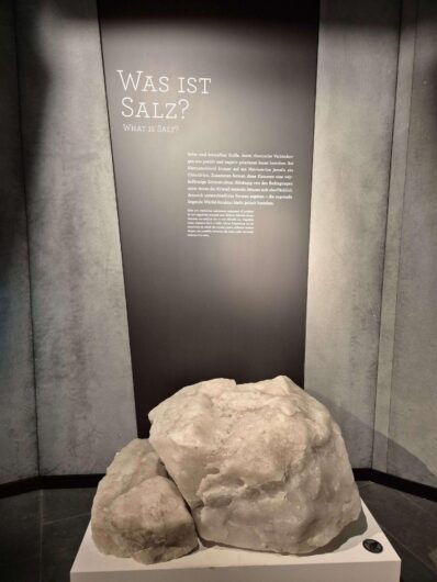 Zwei große helle Salzbrocken auf einem Ausstellungssockel vor einer Informationstafel über Salz in den Westfälischen Salzwelten Bad Sassendorf.