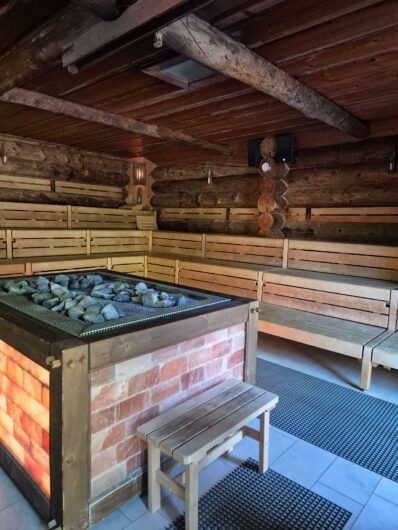 Rustikale Blockhaussauna in der Siedehütte der Börde-Therme Bad Sassendorf mit zentralem Saunaofen und mehrstufigen Holzbänken.