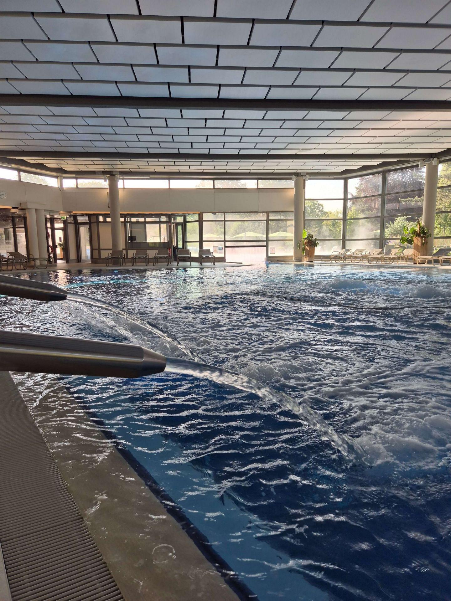 Sprudeldüsen und kräftige Wasserstrahlen im Innenbecken der Börde-Therme Bad Sassendorf mit Blick auf große Fenster.