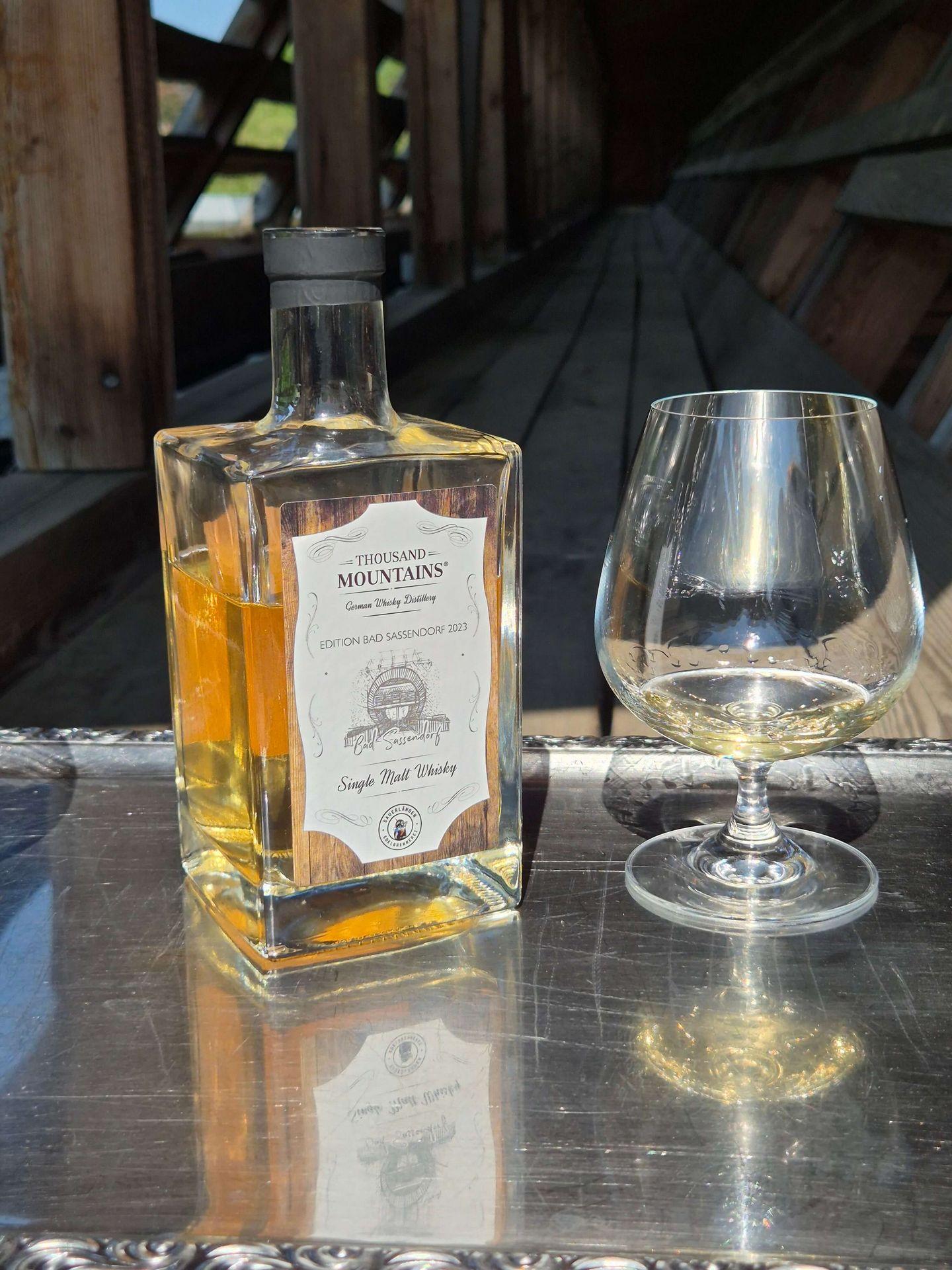 Flasche Thousand Mountains Single Malt Whisky Edition Bad Sassendorf 2023 neben einem Whiskyglas auf einem Tisch im Gradierwerk.